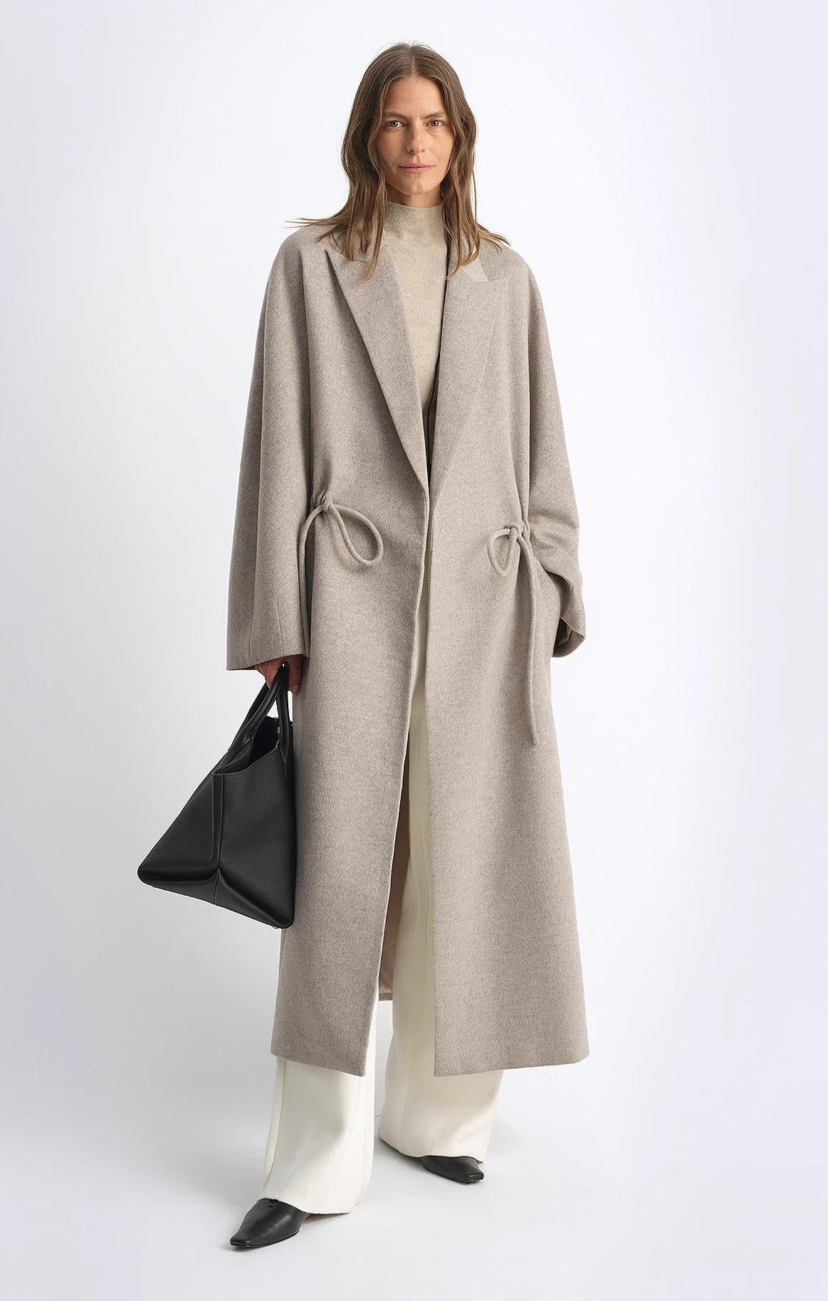 Women's wool coat with peaked lapel and drawstring waist, in a desert hue, by Firelady Fur. Mid-length, stylish outerwear.